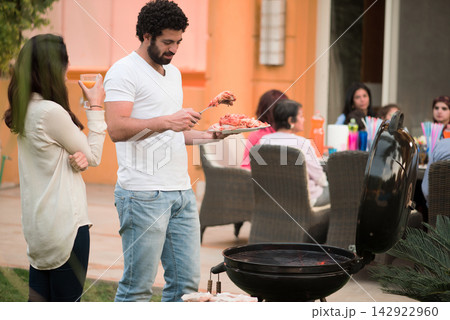Middle Eastern family and friends enjoying Eid iftar barbecue dinner at a modern home 142922960
