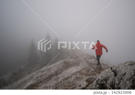 Trail Runner In Red Jacket Running Along Foggy Mountain Ridge In Frosty Winter Landscape Trail Runner In Red Jacket Running Along Foggy Mountain Ridge In Frosty Winter Landscape 142923006