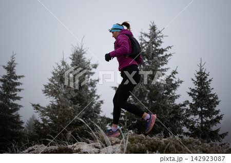 Trail Runner Jogging Through Frosty Mountain Forest On A Cold Winter Morning For Outdoor Fitness Trail Runner Jogging Through Frosty Mountain Forest On A Cold Winter Morning For Outdoor Fitness 142923087