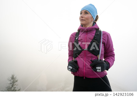 Confident Female Hiker in Pink Jacket and Blue Beanie Standing Outdoors in Foggy Winter Landscape Confident Female Hiker in Pink Jacket and Blue Beanie Standing Outdoors in Foggy Winter Landscape 142923106