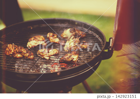 Middle Eastern family grilling chicken outdoors: modern Arab lifestyle barbecue and summer gathering in the backyard Middle Eastern family grilling chicken outdoors: modern Arab lifestyle barbecue and summer gathering in the backyard 142923151