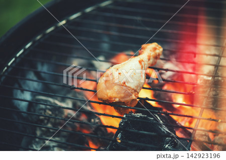 Grilled chicken drumstick on charcoal barbecue evoking Middle Eastern modern Arab family lifestyle and outdoor cooking Grilled chicken drumstick on charcoal barbecue evoking Middle Eastern modern Arab family lifestyle and outdoor cooking 142923196