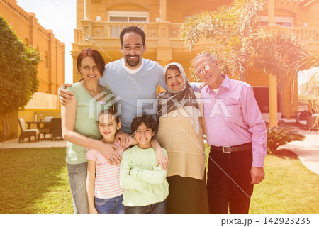 Middle Eastern modern Arab family enjoying multigenerational outdoor time at home in sunny courtyard Middle Eastern modern Arab family enjoying multigenerational outdoor time at home in sunny courtyard 142923235