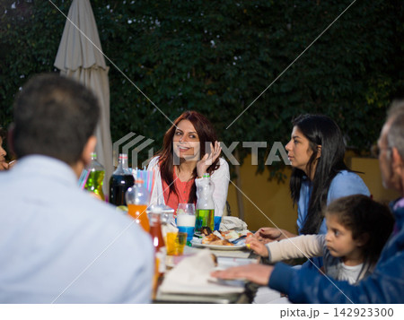 Middle Eastern Arab multi generation family enjoying outdoor dinner at a modern luxury villa with friends and children Middle Eastern Arab multi generation family enjoying outdoor dinner at a modern luxury villa with friends and children 142923300