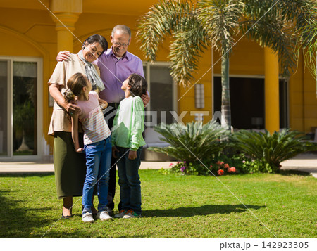 Middle Eastern Arab multi generation family embracing in front of modern luxury villa garden Middle Eastern Arab multi generation family embracing in front of modern luxury villa garden 142923305