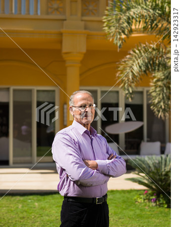 Middle Eastern man standing confidently in front of modern luxury villa, part of multi-generation Arab family Middle Eastern man standing confidently in front of modern luxury villa, part of multi-generation Arab family 142923317