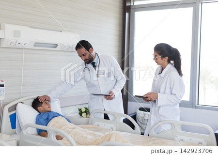 Middle Eastern doctors examining a young boy in an eye hospital clinic in Egypt, compassionate pediatric care team Middle Eastern doctors examining a young boy in an eye hospital clinic in Egypt, compassionate pediatric care team 142923706
