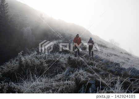 Couple Hiking on Frosty Mountain Trail in Foggy Morning Light Couple Hiking on Frosty Mountain Trail in Foggy Morning Light 142924105
