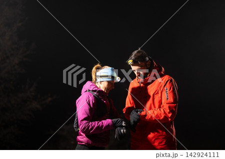 Couple Night Hikers Checking Gear With Headlamps During Cold Outdoor Winter Adventure In Wilderness Couple Night Hikers Checking Gear With Headlamps During Cold Outdoor Winter Adventure In Wilderness 142924111