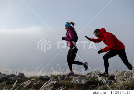 Trail Running Couple In Winter Mountains Training Together On A Frosty Rocky Ridge 142924115
