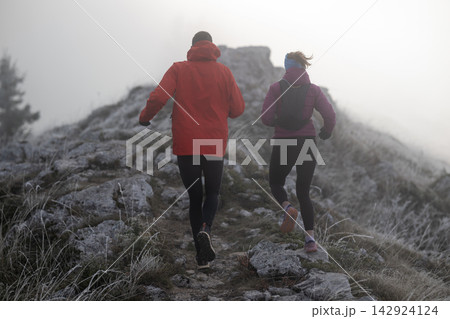 Couple Trail Runners Jogging Up Foggy Mountain Path In Cold Winter Morning Outdoor Fitness Training 142924124