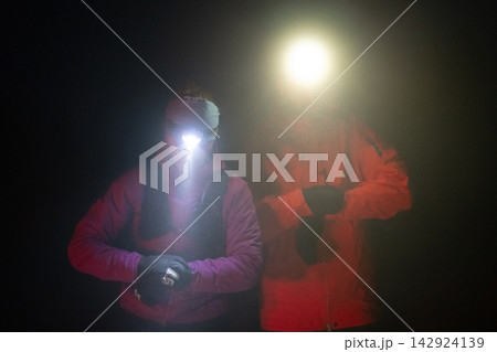Two Hikers Wearing Headlamps at Night During Cold Weather Trekking and Outdoor Adventure 142924139
