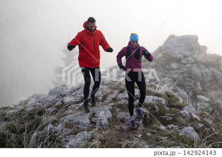 Couple Trail Running on Foggy Mountain Ridge During Cold Weather Training Run Couple Trail Running on Foggy Mountain Ridge During Cold Weather Training Run 142924143