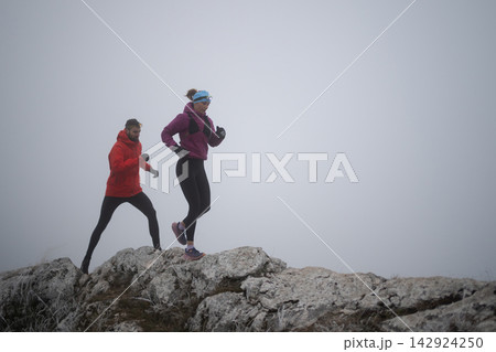 Trail Running Couple on Foggy Mountain Ridge With Headlamps for Winter Fitness Training 142924250