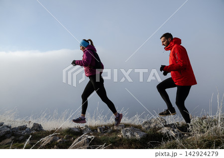 Couple Trail Runners Jogging On Frosty Mountain Ridge In Winter Outdoor Fitness Couple Trail Runners Jogging On Frosty Mountain Ridge In Winter Outdoor Fitness 142924279