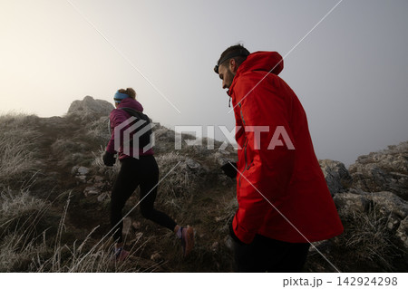 Couple Trail Running and Hiking Up Frosty Mountain Ridge in Foggy Cold Outdoor Adventure Couple Trail Running and Hiking Up Frosty Mountain Ridge in Foggy Cold Outdoor Adventure 142924298