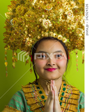 Young Indonesian Asian Girl in Traditional Thai Gold Headdress and Costume Performing Wai Greeting in Portrait Young Indonesian Asian Girl in Traditional Thai Gold Headdress and Costume Performing Wai Greeting in Portrait 142924326