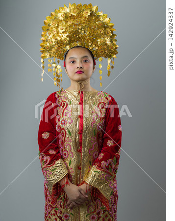 Portrait Of Indonesian Asian Woman Wearing Traditional Ceremonial Costume With Ornate Gold Headdress And Embroidered Robe Portrait Of Indonesian Asian Woman Wearing Traditional Ceremonial Costume With Ornate Gold Headdress And Embroidered Robe 142924337