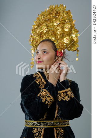 Young Indonesian Asian Woman Wearing Ornate Gold Traditional Headdress And Embroidered Velvet Costume Portrait Young Indonesian Asian Woman Wearing Ornate Gold Traditional Headdress And Embroidered Velvet Costume Portrait 142924427