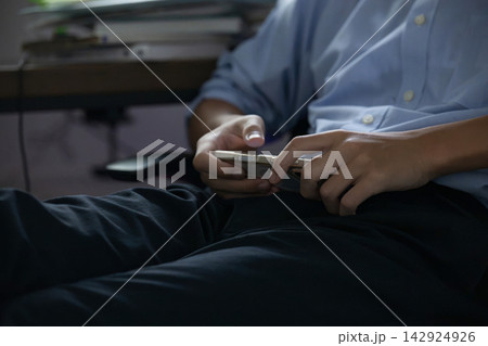 自宅で勉強に集中せずスマホを触る学生、学習中にスマートフォンに触れる学生イメージ、ドーパミン中毒注意 自宅で勉強に集中せずスマホを触る学生、学習中にスマートフォンに触れる学生イメージ、ドーパミン中毒注意 142924926