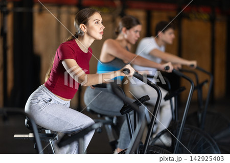 Focused girl works out with airbike during class at fitness club 142925403