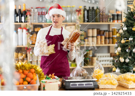 European guy seller stands in trading hall grocery, offer to buy sweets at New Year Eve 142925433