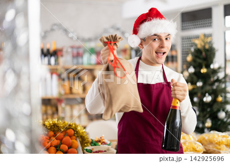 Young guy seller with champagne and bag Young guy seller with champagne and bag 142925696