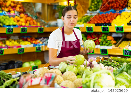 Portrait of happy woman in apron selling organic zucchini in shop Portrait of happy woman in apron selling organic zucchini in shop 142925699