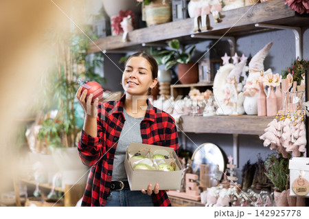 The excited young woman checking the material of Christmas bubbles while standing in a decorated hall The excited young woman checking the material of Christmas bubbles while standing in a decorated hall 142925778