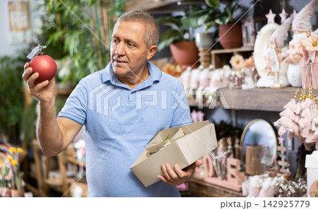Middle-aged male consumer choosing Christmas decorations in a shopping mall at the December Middle-aged male consumer choosing Christmas decorations in a shopping mall at the December 142925779