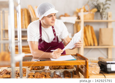 Bakery guy employee in apron examines documents, ponders debt restructuring 142925791