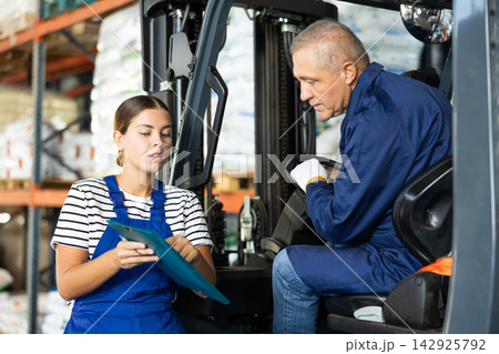 Young woman and elderly man working on loader check documents Young woman and elderly man working on loader check documents 142925792