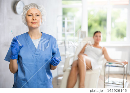 Adult female doctor posing with syringe in medical room Adult female doctor posing with syringe in medical room 142926146