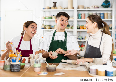 Joyous young man and women sculpting handmade cups Joyous young man and women sculpting handmade cups 142926160