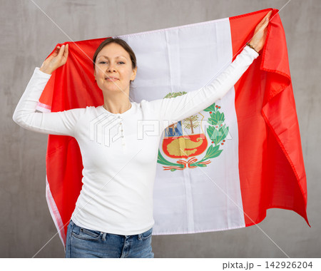 Smiling woman waving flag of Peru against gray background Smiling woman waving flag of Peru against gray background 142926204