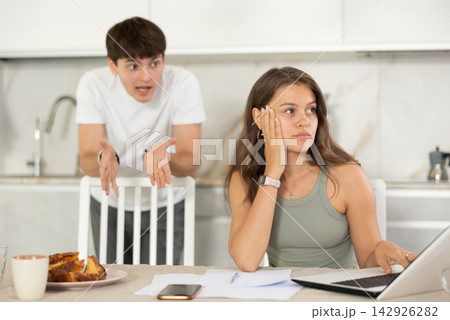 Young guy quarrels with young woman working at laptop Young guy quarrels with young woman working at laptop 142926282