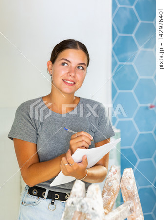 Young woman makes notes on paper while standing in the bathroom Young woman makes notes on paper while standing in the bathroom 142926401