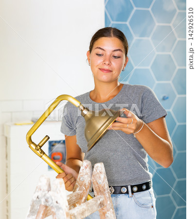Young woman holds a shower head in the bathroom 142926510