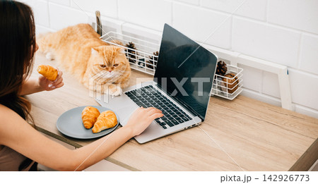 Heartwarming home office portrait, woman exemplifies joy of togetherness with her Scottish Fold cat while focusing on work at her desk, creating harmonious blend of productivity and pet companionship. Heartwarming home office portrait, woman exemplifies joy of togetherness with her Scottish Fold cat while focusing on work at her desk, creating harmonious blend of productivity and pet companionship. 142926773