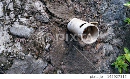 Drainage pipe in a weathered stone wall Drainage pipe in a weathered stone wall 142927515