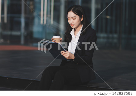 Young brunette business lady dressed in black jacket checking work chats sitting outside with laptop Young brunette business lady dressed in black jacket checking work chats sitting outside with laptop 142927595