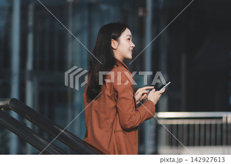 Young businesswoman smiling while working with digital tablet at modern office building 142927613