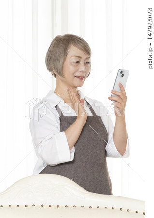 リビングでスマホを使いこなすシニア女性 リビングでスマホを使いこなすシニア女性 142928028