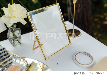 Blank gold photo frame mockup on wedding table with white rose. Blank gold photo frame mockup on wedding table with white rose. 142928273