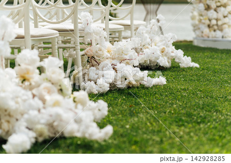 Wedding arch decorated with flowers and lights and white chairs for guests. Wedding ceremony. Wedding arch decorated with flowers and lights and white chairs for guests. Wedding ceremony. 142928285