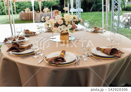 Elegant wedding table setting with floral centerpiece and candles under a marquee tent. 142928306
