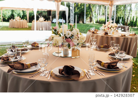 Elegant wedding table setting with floral centerpiece and candles under a marquee tent. Elegant wedding table setting with floral centerpiece and candles under a marquee tent. 142928307