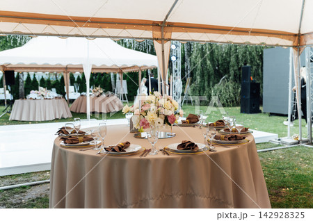 Elegant wedding table setting with floral centerpiece and candles under a marquee tent. 142928325