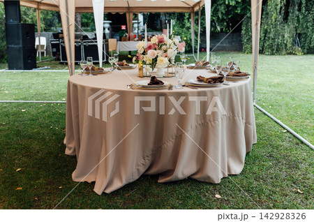 Elegant wedding table setting with floral centerpiece and candles under a marquee tent. Elegant wedding table setting with floral centerpiece and candles under a marquee tent. 142928326