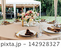 Elegant wedding table setting with floral centerpiece and candles under a marquee tent. 142928327